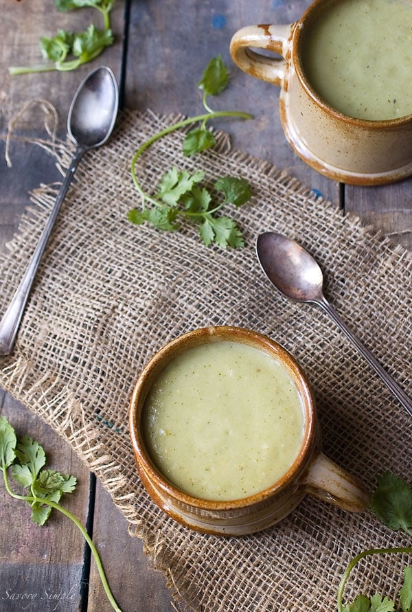 Chilled tomatillo avocado soup in mugs on a wood backdrop