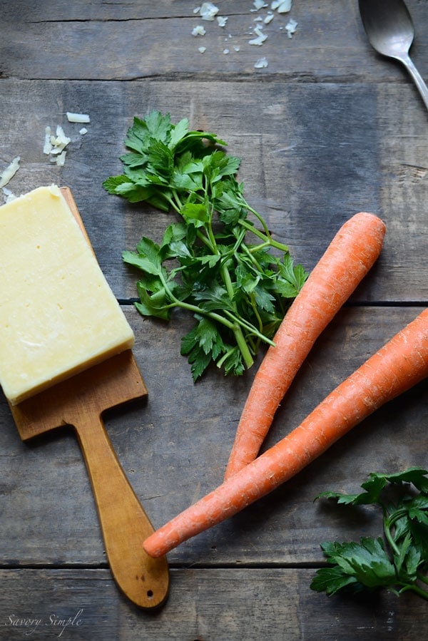 A photo of ingredients for potato soup, including cheese, parsley, and carrots.