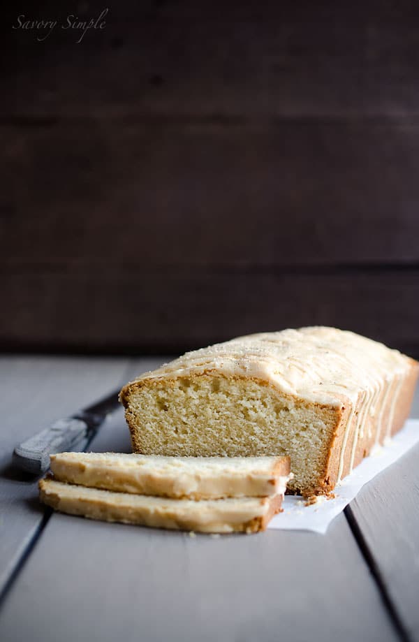 This Eggnog Poundcake with Rum Glaze is moist, dense, sweet and eggy. It's a fabulous holiday dessert! Sliced eggnot poundcake on a wood backdrop.