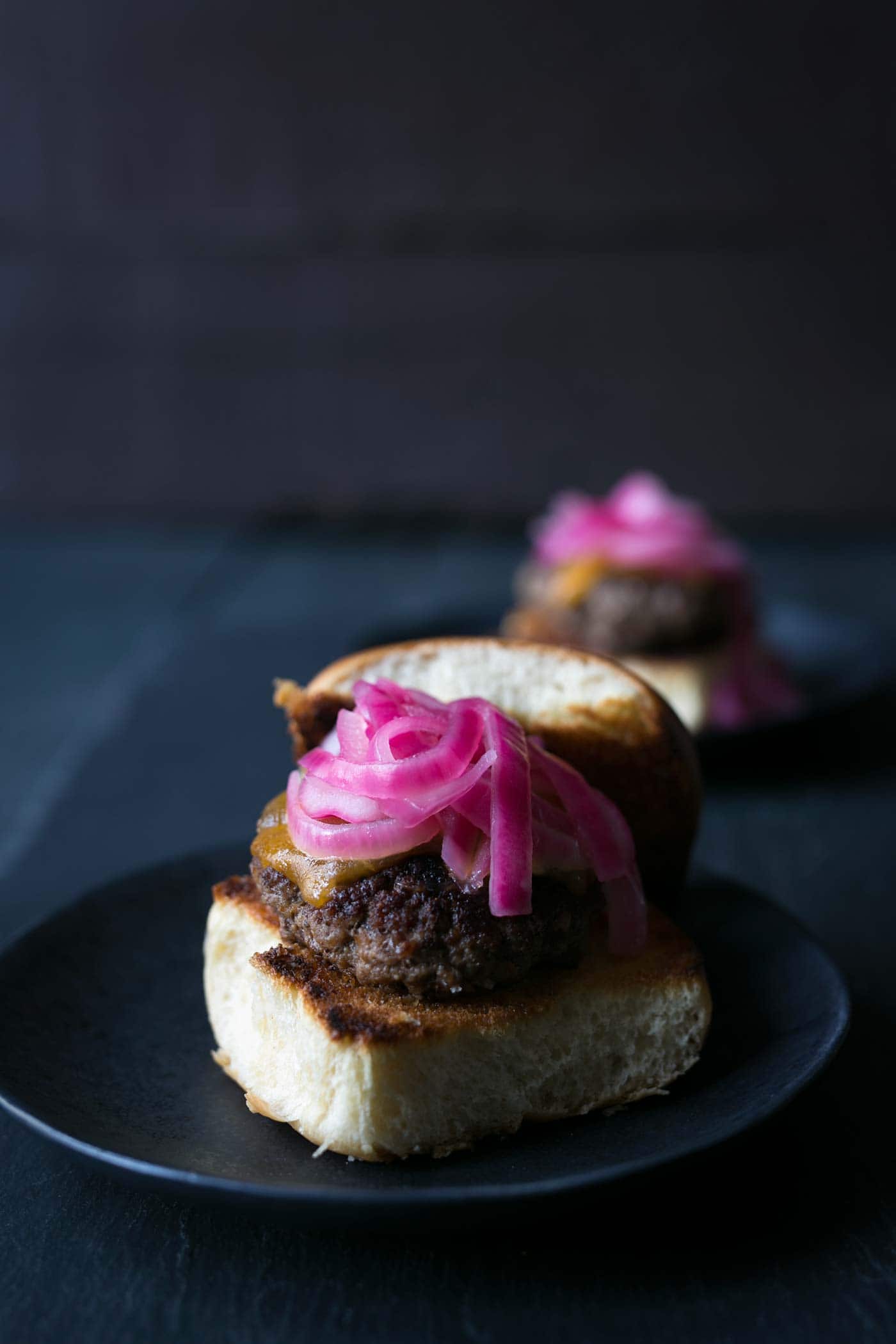 These Cheeseburger Sliders with Quick Pickled Onions are the PERFECT combinations of flavors and texture. They are also so easy to make! Get the recipe from SavorySimple.net.