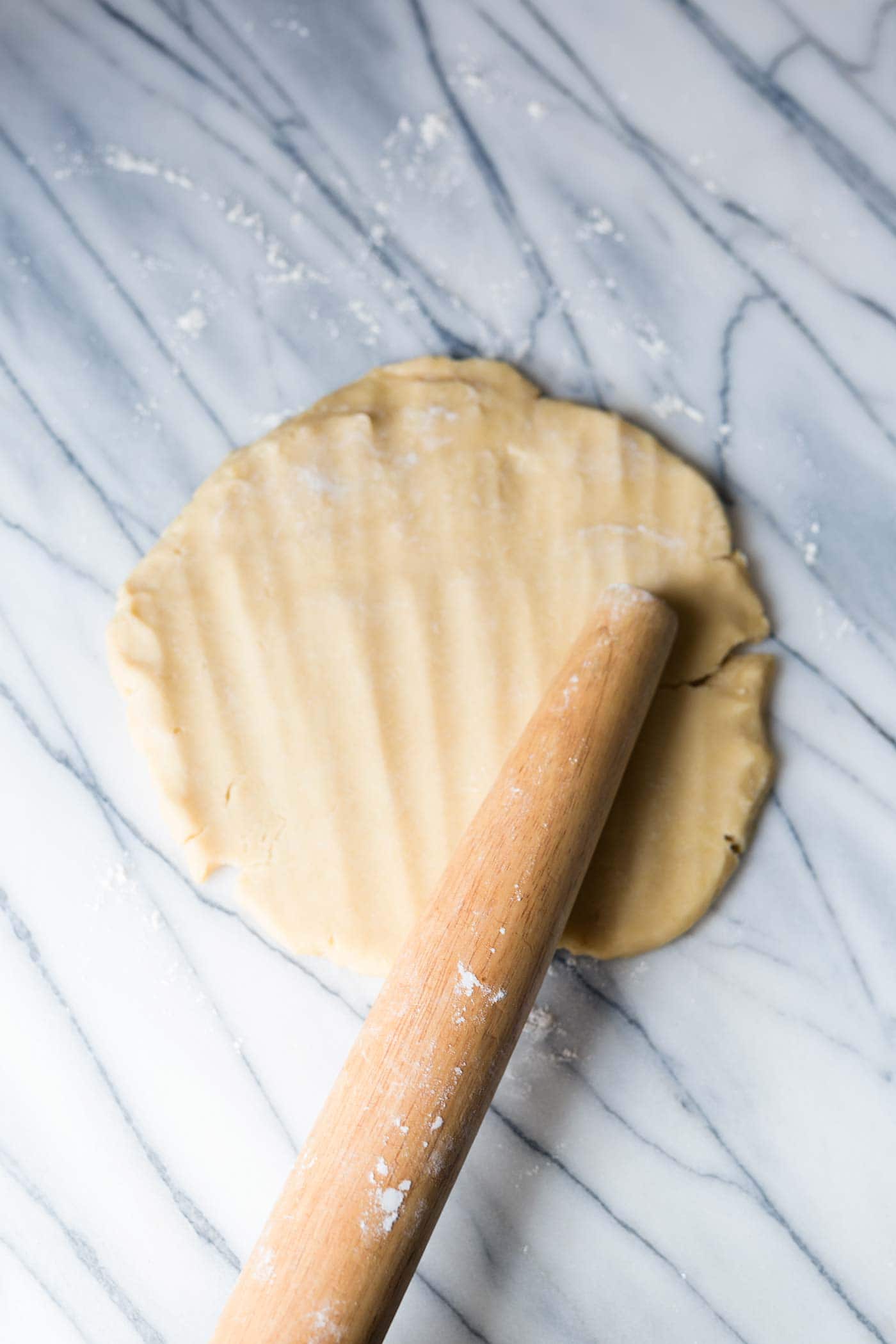 Tart dough being flattened with a rolling pin.