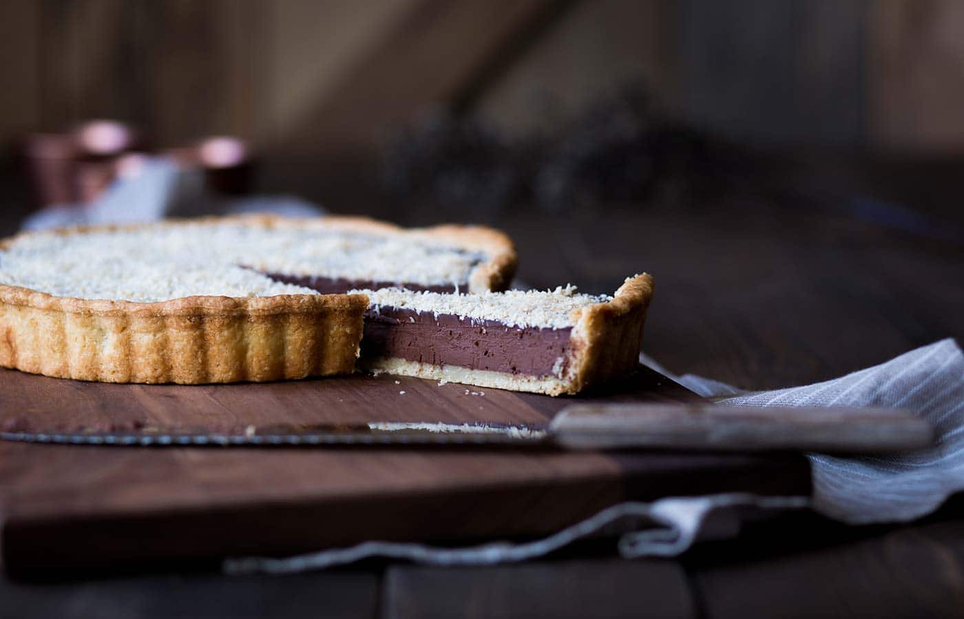 A slice of chocolate tart separated from the full tart.