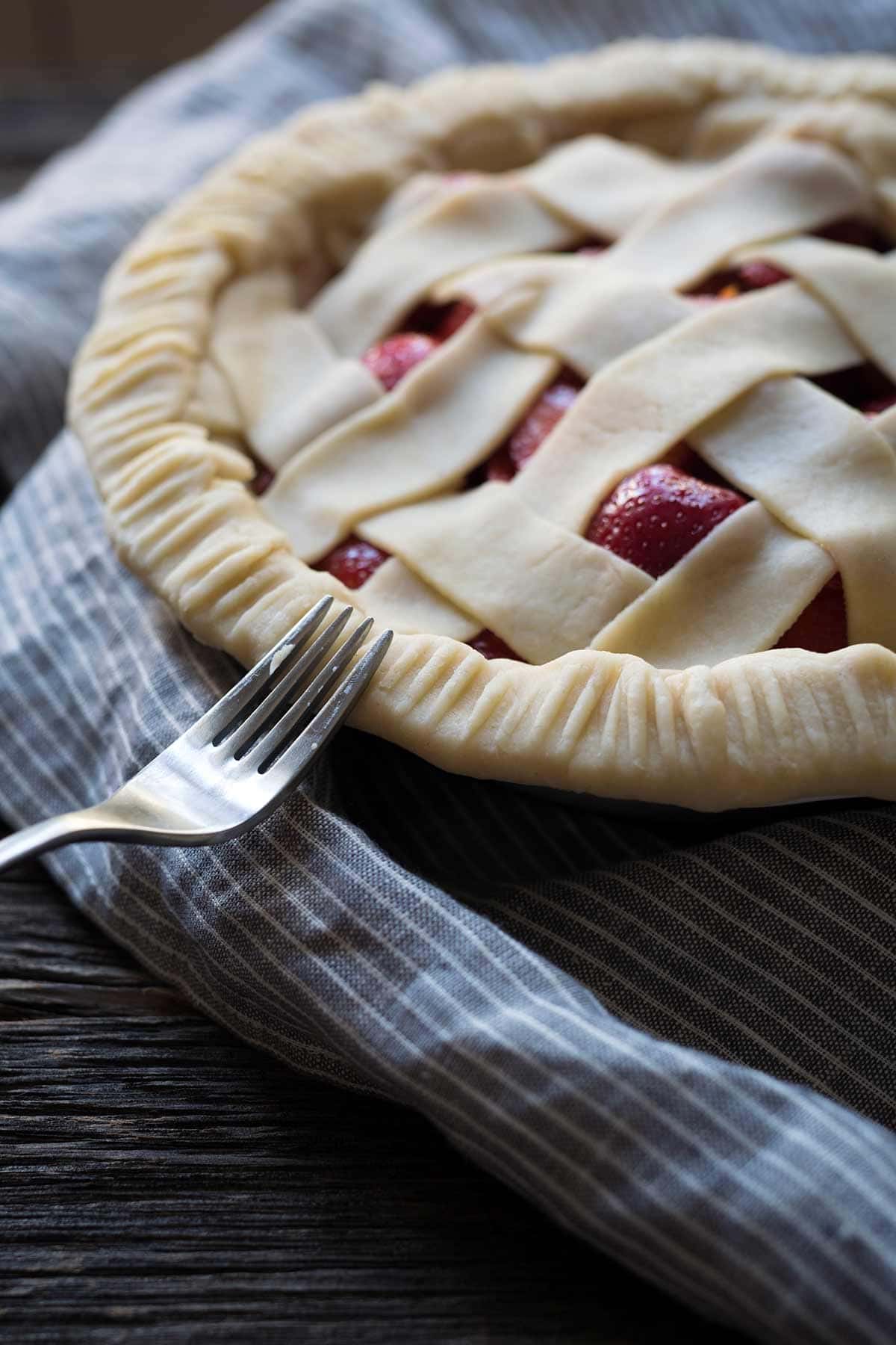 Pressing a fork around the edges of the dough to seal the lattice top edges.