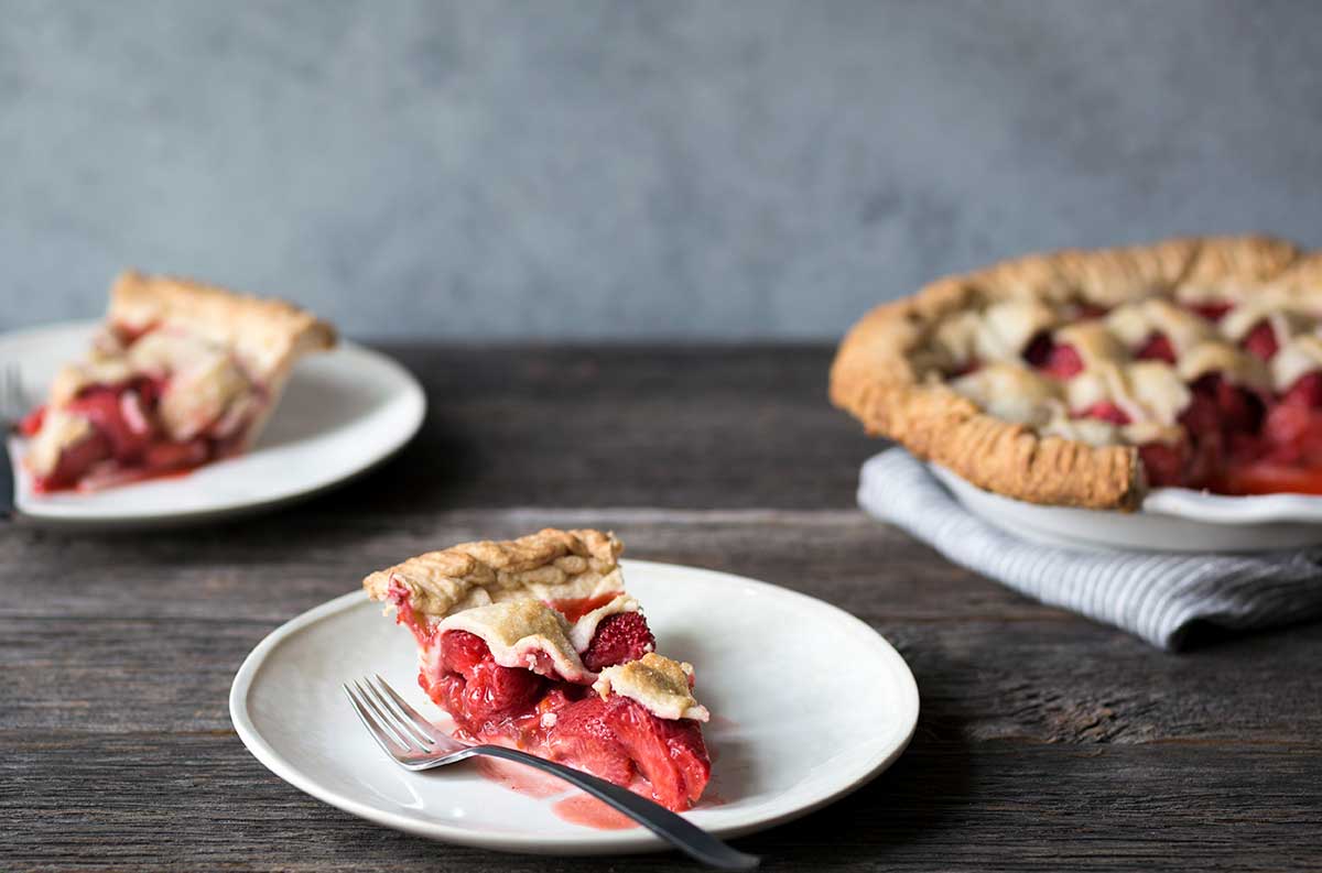 Two slices of strawberry pie next to the remaining pie.