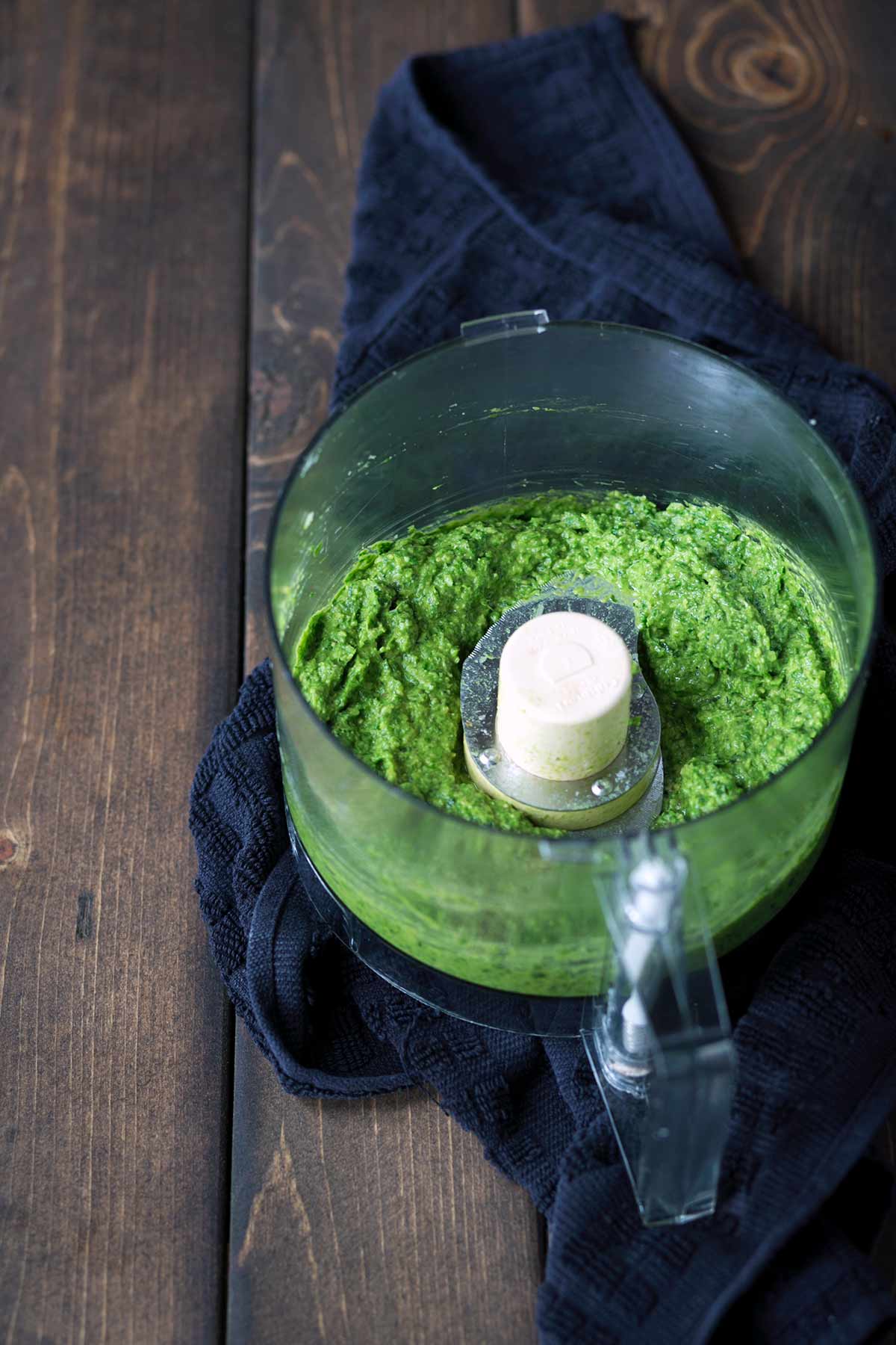 Bright green homemade pesto in a food processor.
