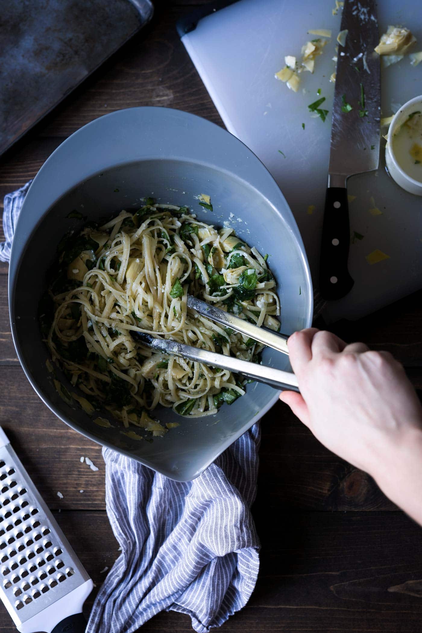 spinach and artichoke pasta ingredients being combined in a bowl
