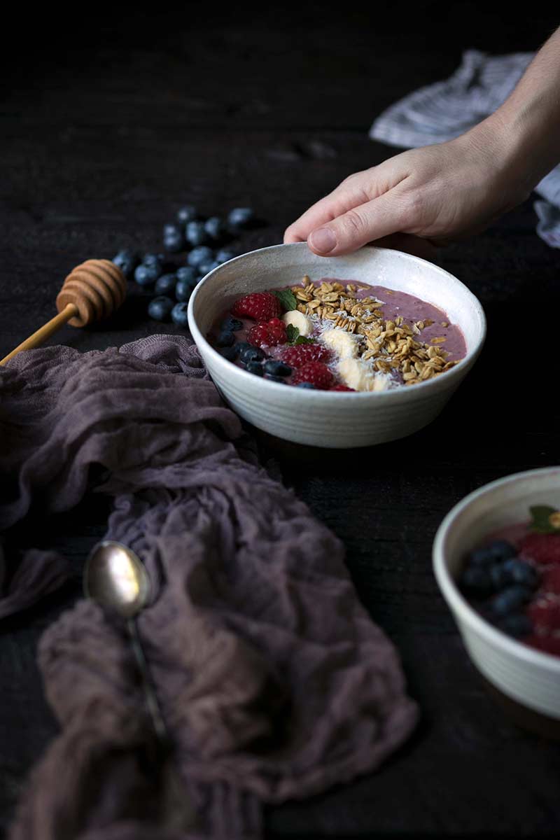 A hand holding an Acai Smoothie Bowl Recipe in a bowl.