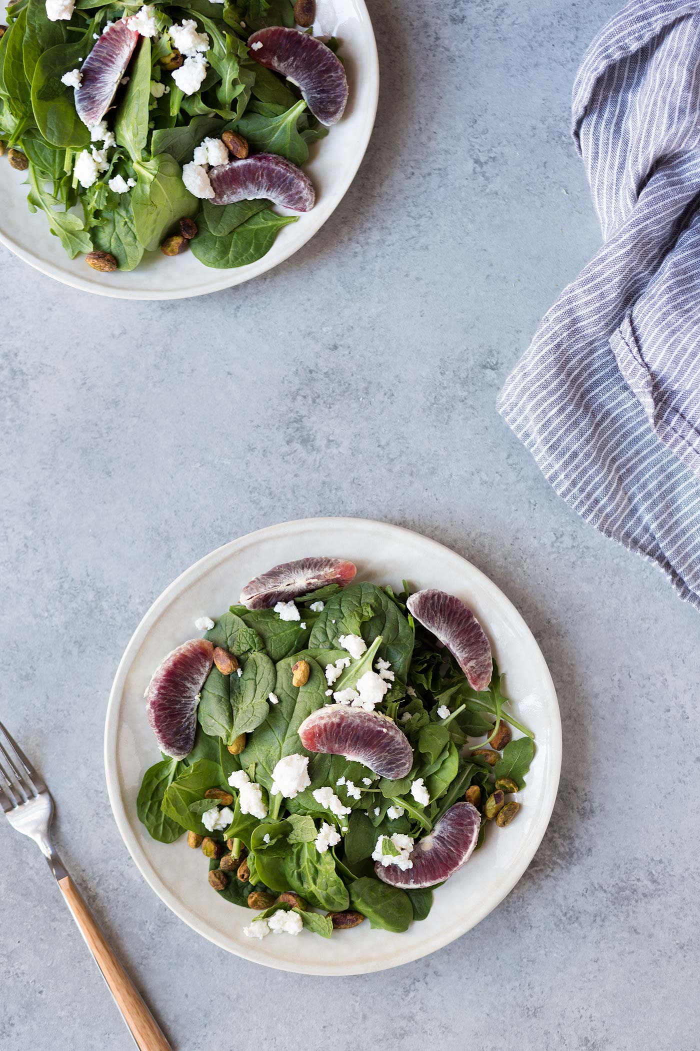 overhead: two plates of spring mix salad with Feta, Blood Oranges, Mint and Pistachios
