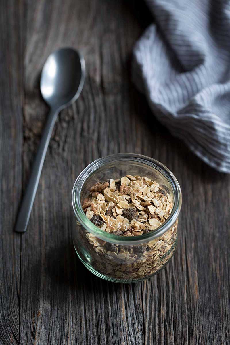 homemade muesli cereal in glass jar next to spoon