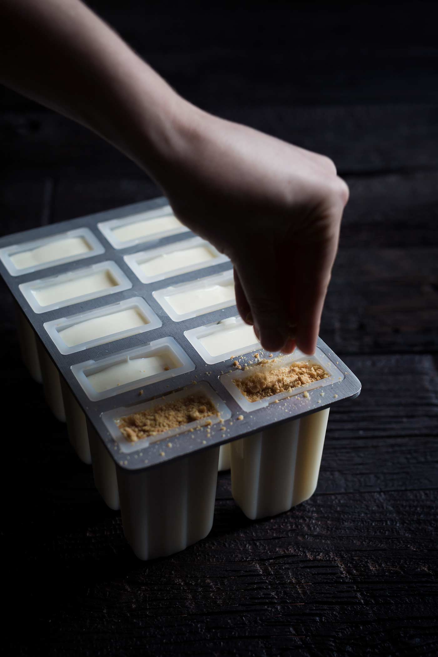A photo demonstrating the graham cracker crumbs being gently pressed on top of the filling