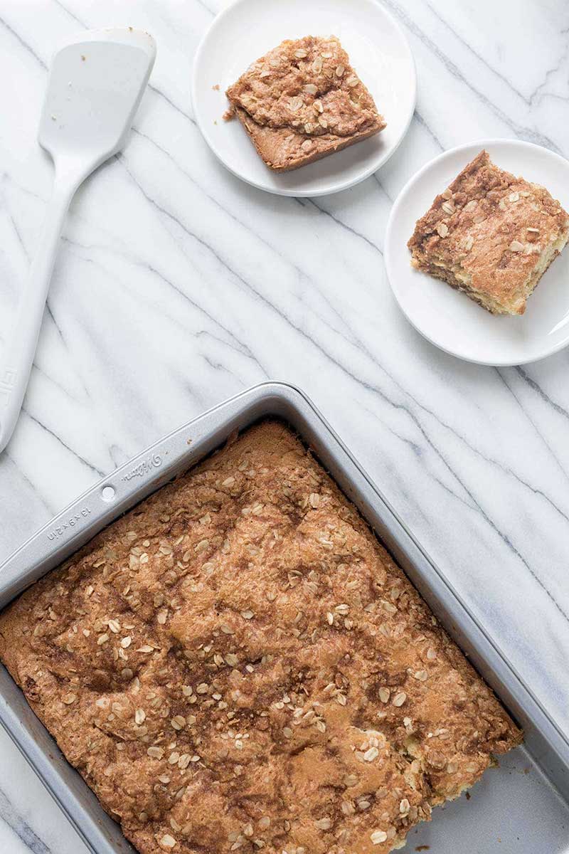 overhead photo: pan of streusel coffee cake. with two plated slices next to it