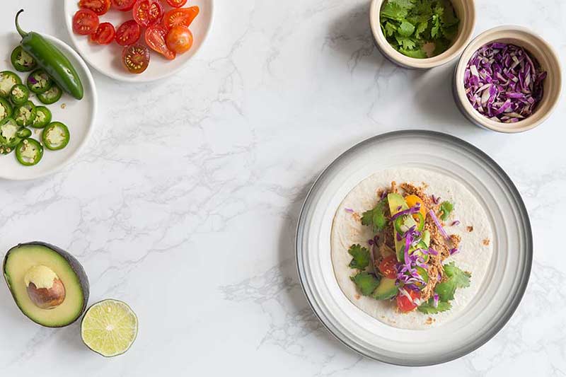A photo of the finished easy chicken taco recipe surrounded by some accompaniments. 