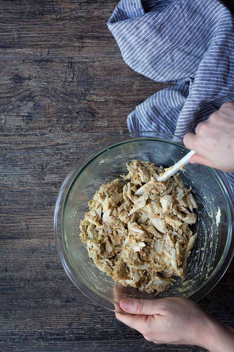 Stirring lump crab meat with crab cake ingredients