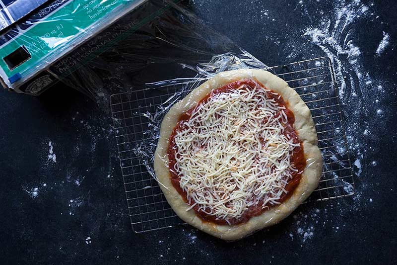A photo of pizza being wrapped in plastic film.