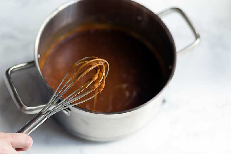 A photo of a whisk dipped into the finished caramel sauce. 