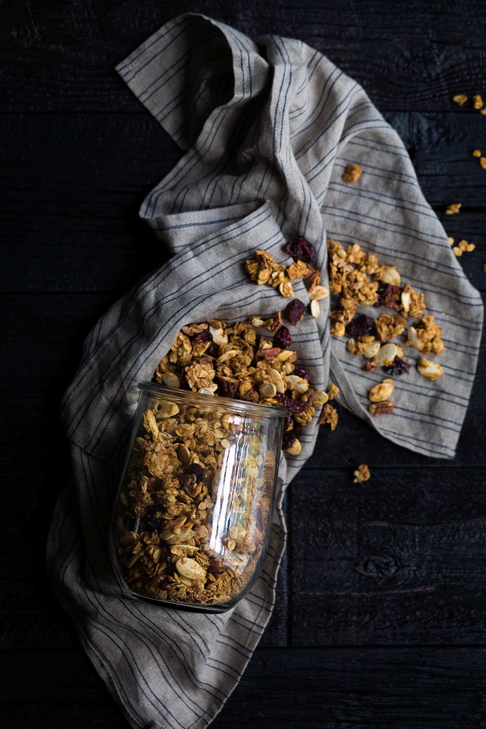 A photo of healthy, homemade pumpkin granola, spilling out of a jar.