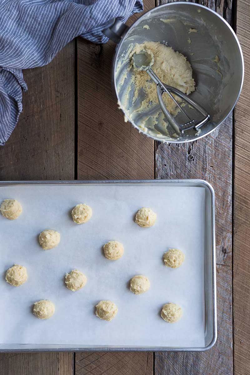 A photo of eggnog cookie dough scooped onto a baking sheet lined with parchment paper.
