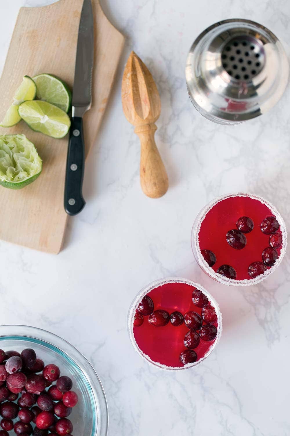 An overhead photo of cranberry margaritas and limes.