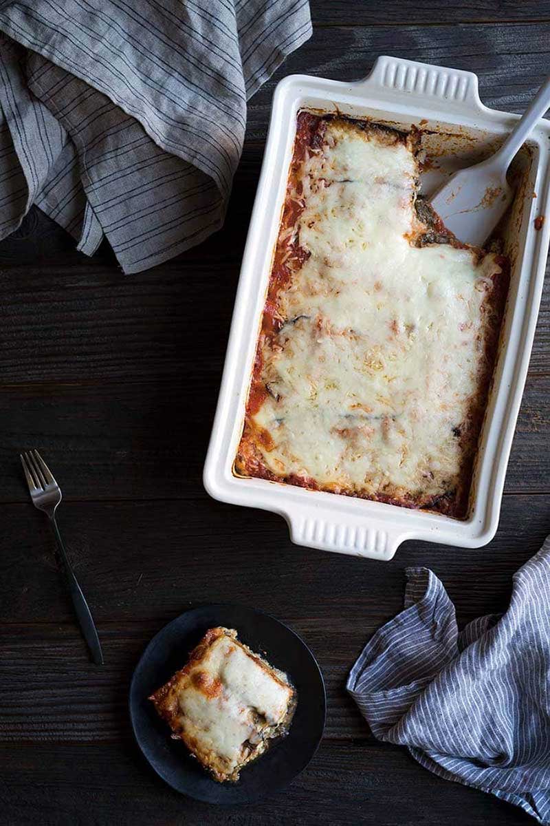 Eggplant lasagna recipe in a casserole dish with one slice on a plate