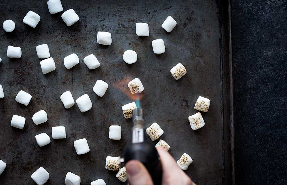 A photo of marshmallows being toasted for a smores dessert