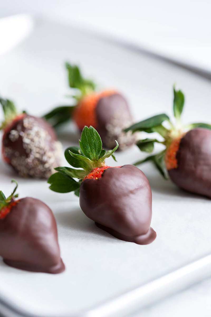 Chocolate covered strawberries on a white serving tray.