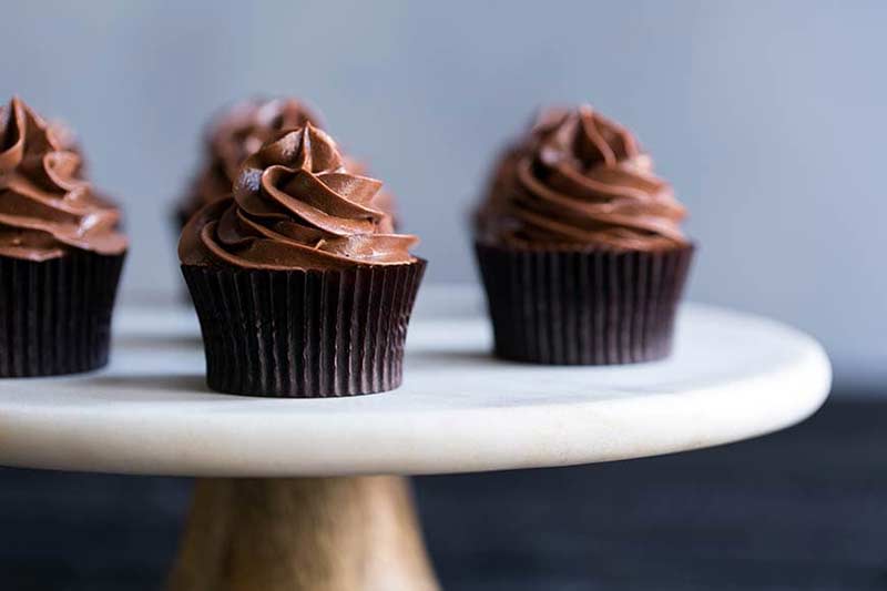 A photo of chocolate cupcakes topped with chocolate meringue buttercream.