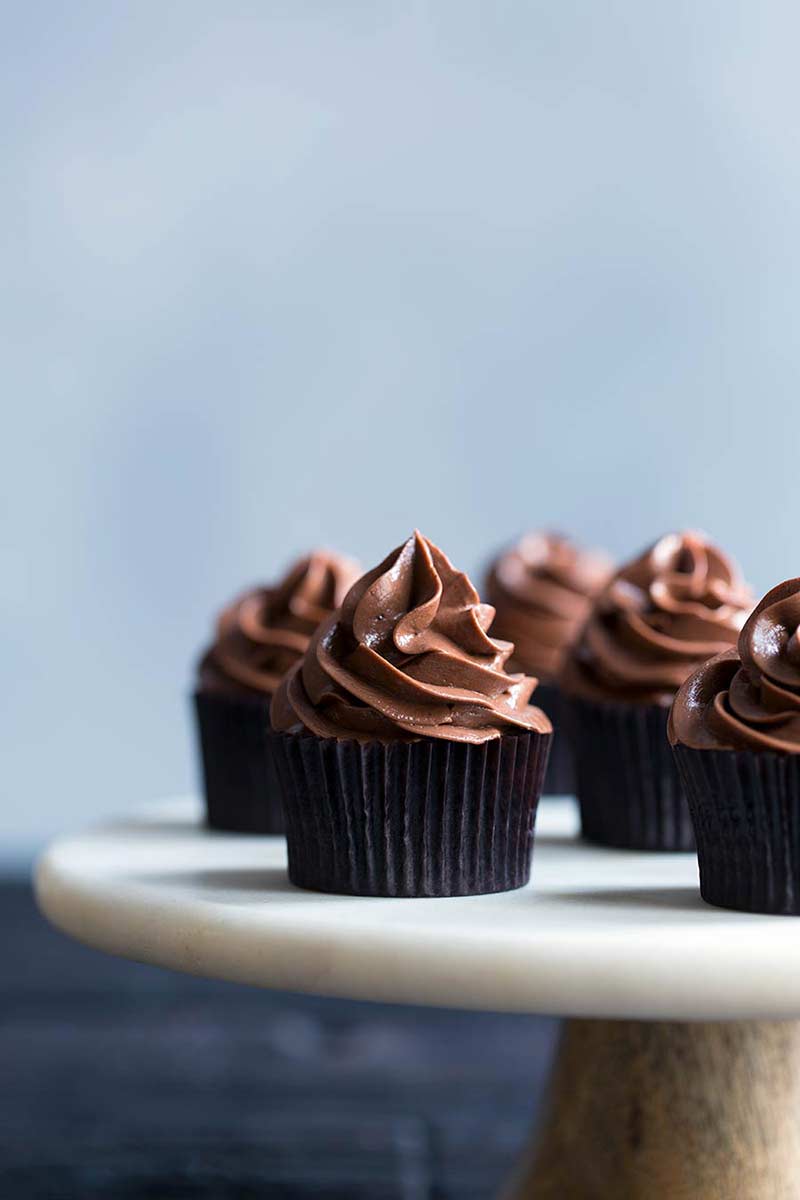 close up photo: swirls of chocolate meringue buttercream frosting on top of cupcakes