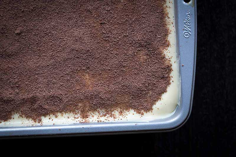cocoa powder dusted over custard layer of homemade tiramisu