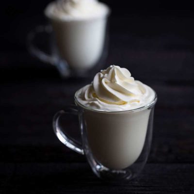hot white chocolate in mugs topped with whipped cream