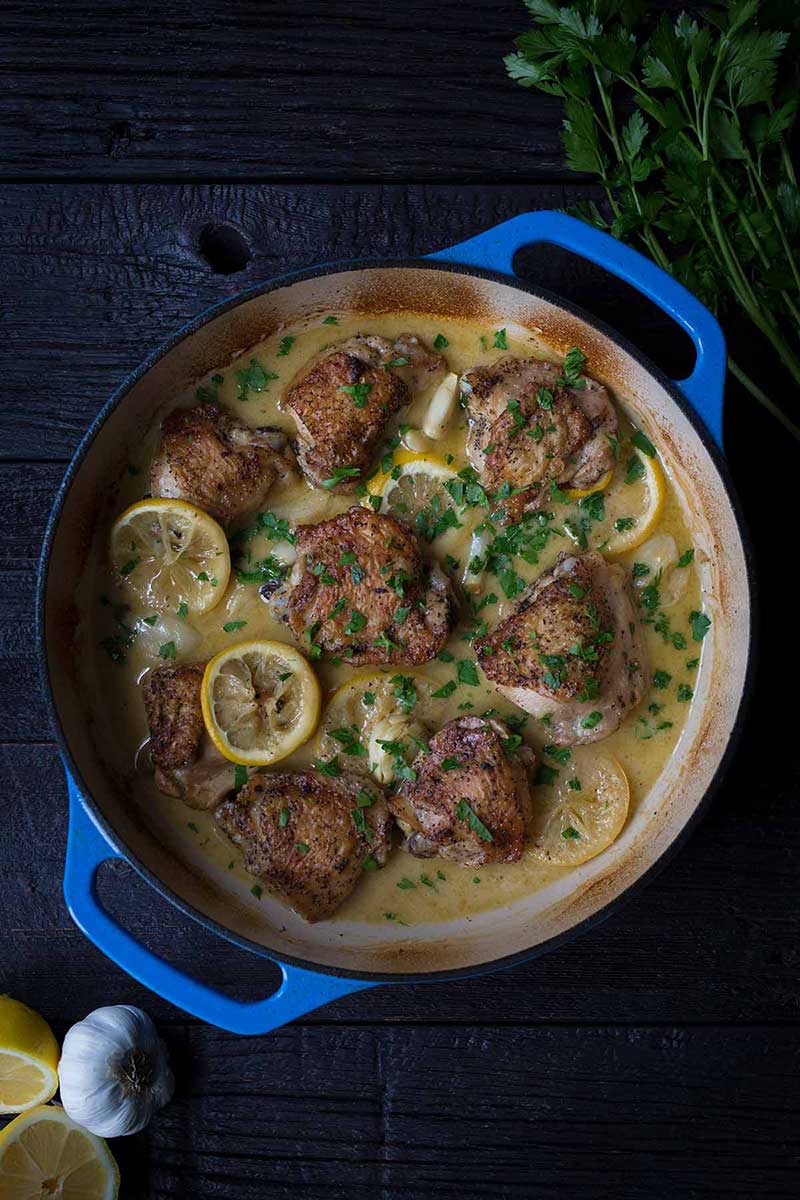 A photo of crispy baked chicken thighs in a blue casserole dish