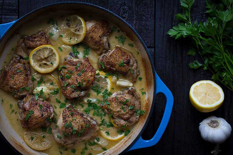 A photo of crispy garlic and lemon chicken thighs in a round casserole dish