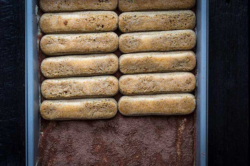 Tiramisu process shot with ladyfingers spread halfway over a layer of custard