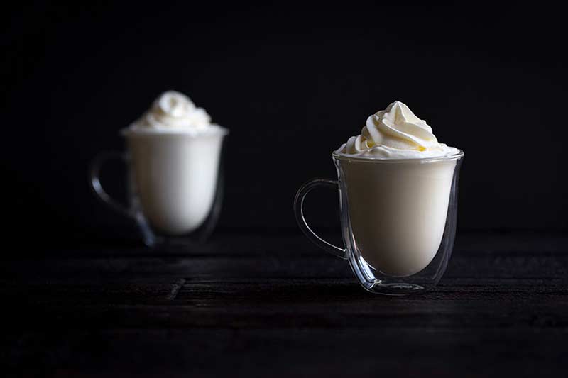 Two cups of hot chocolate topped with whipped cream.