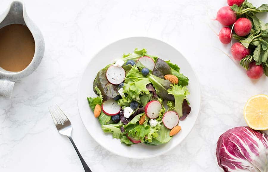 A colorful salad surrounded by vibrant vegetables.