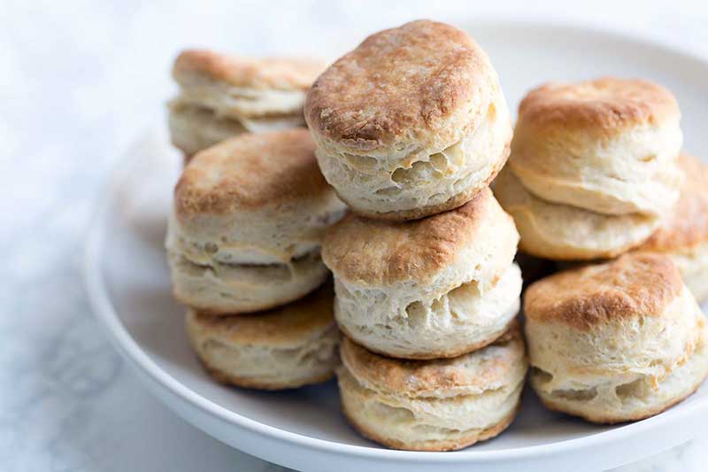 A photo of the finished buttermilk biscuits stacked high on a serving plate.