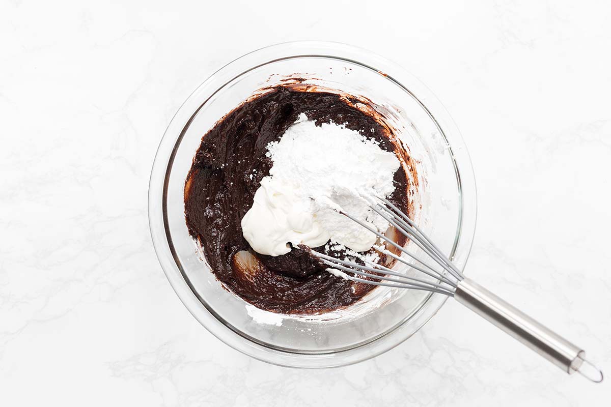 Whisking confectioners' sugar into the other chocolate frosting ingredients.