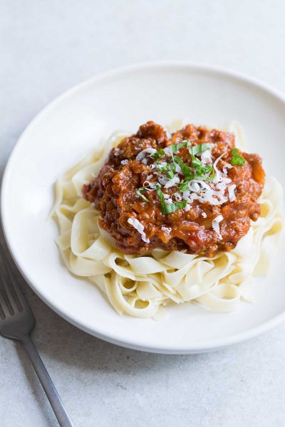 Homemade meat sauce served over freshly cooked pasta, topped with grated parmesan and basil.