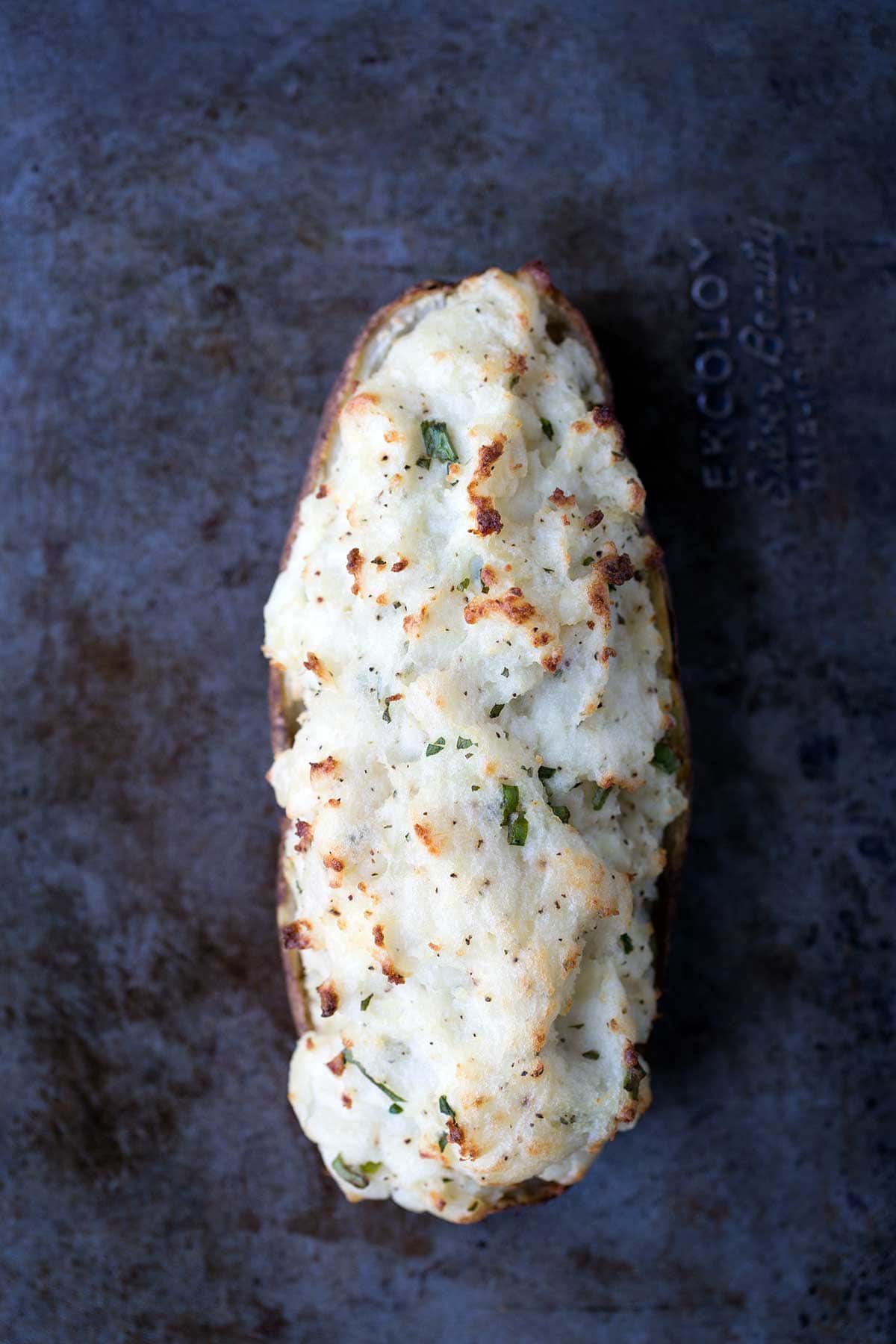 An overhead shot of a single twice-baked potato on a baking sheet.