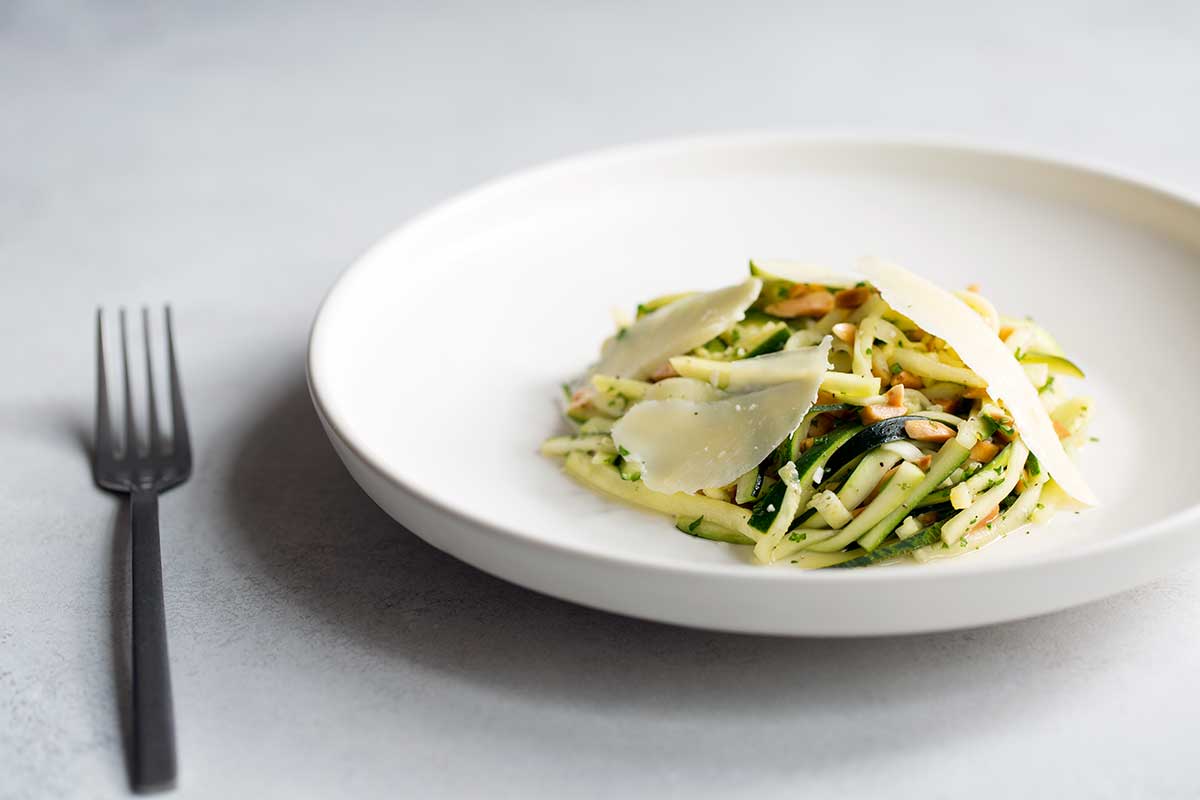 Photo of zucchini salad recipe on a pale backdrop.