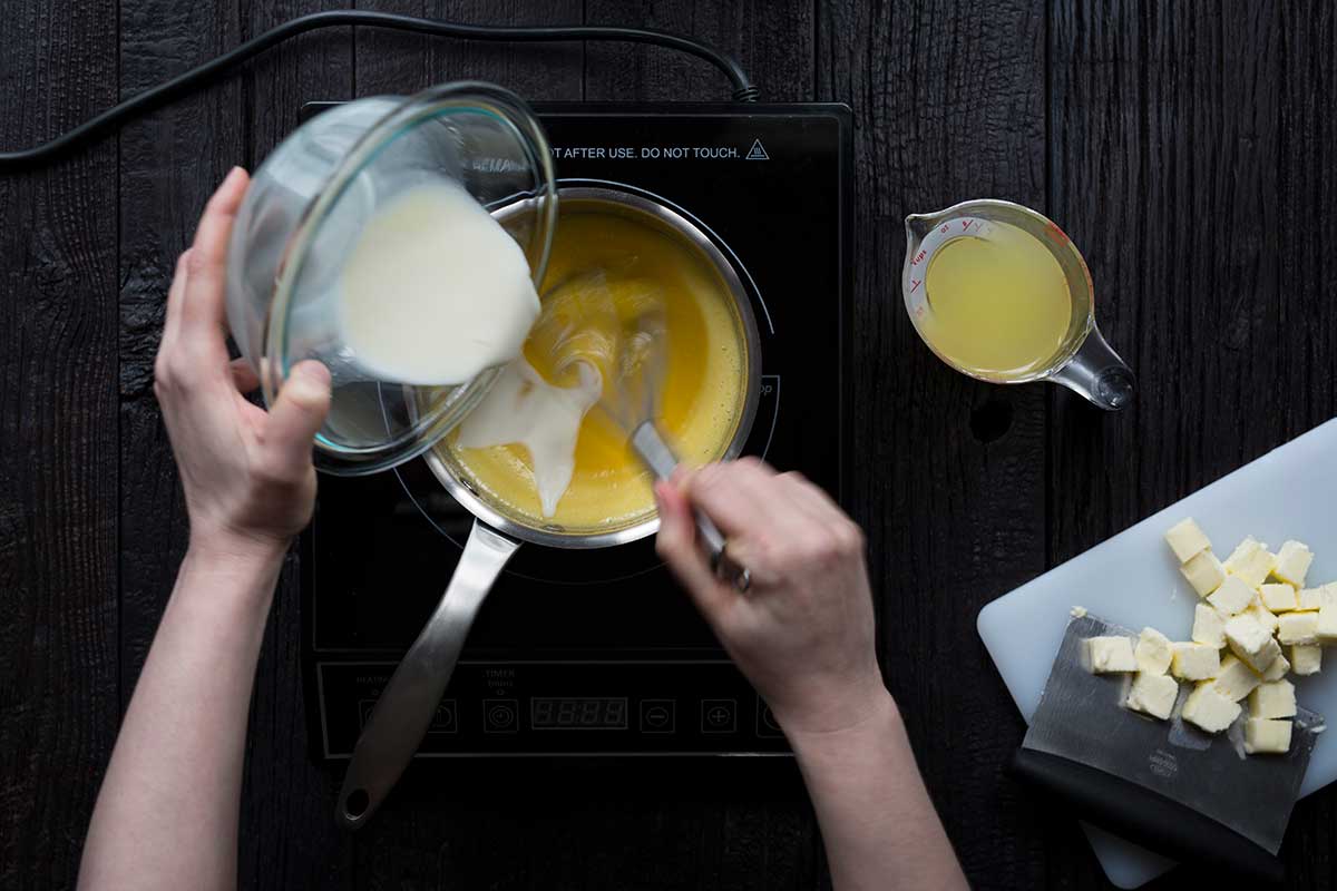 Pouring the slurry into the egg and sugar mixture while whisking.