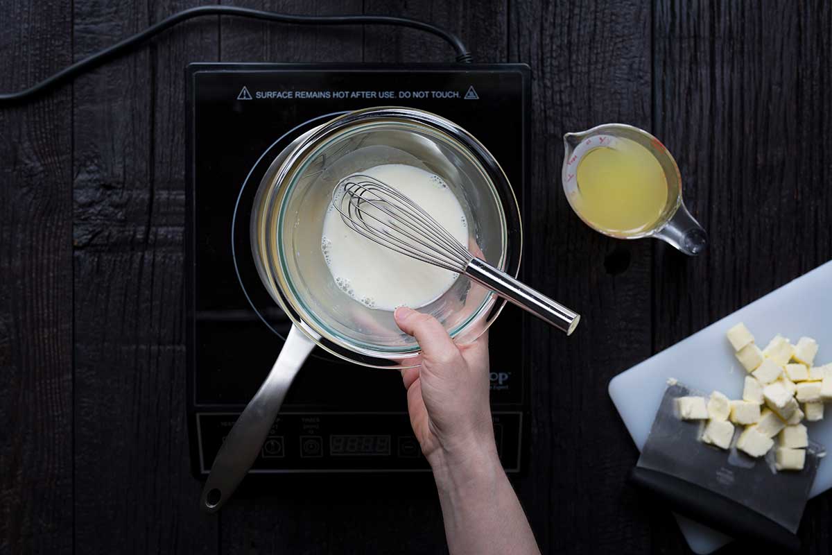 A bowl containing a whisk and a slurry made from cornstarch and fresh lemon juice.