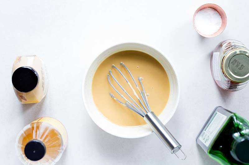 Honey mustard dressing in a bowl with a whisk.