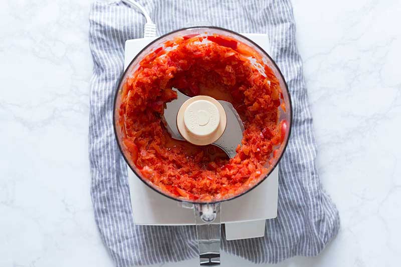 Chopped red bell peppers in a food processor.