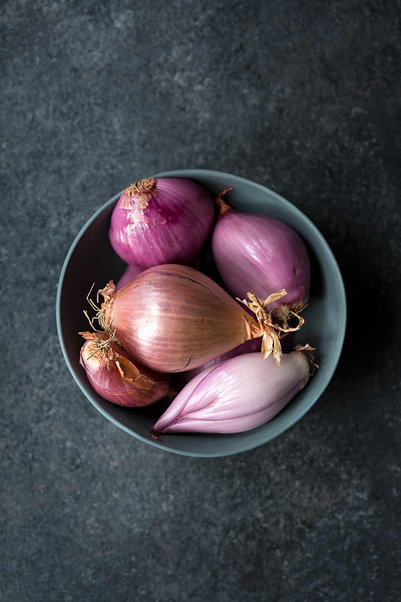 Shallots of various shapes and sizes in a bowl.