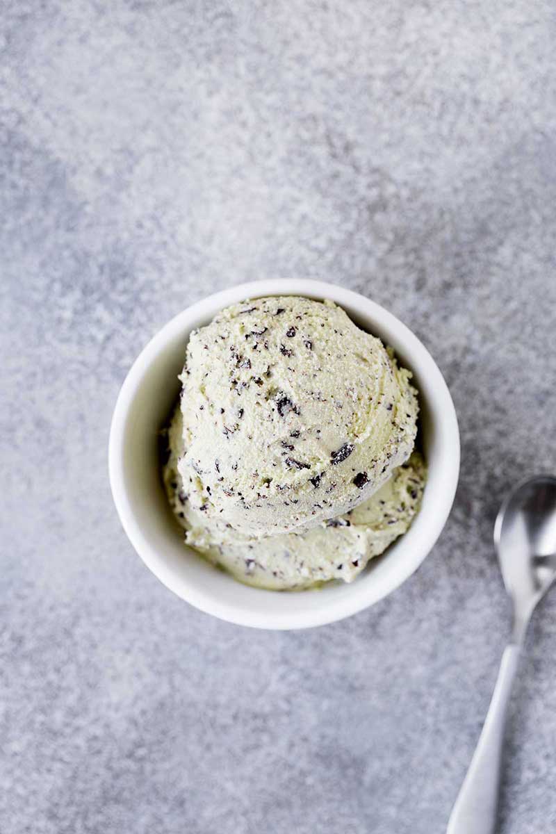 custard cup of frozen dairy dessert on gray background with spoon next to it