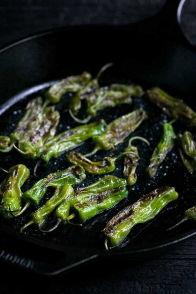 side angle closeup of blistered shishito peppers recipe