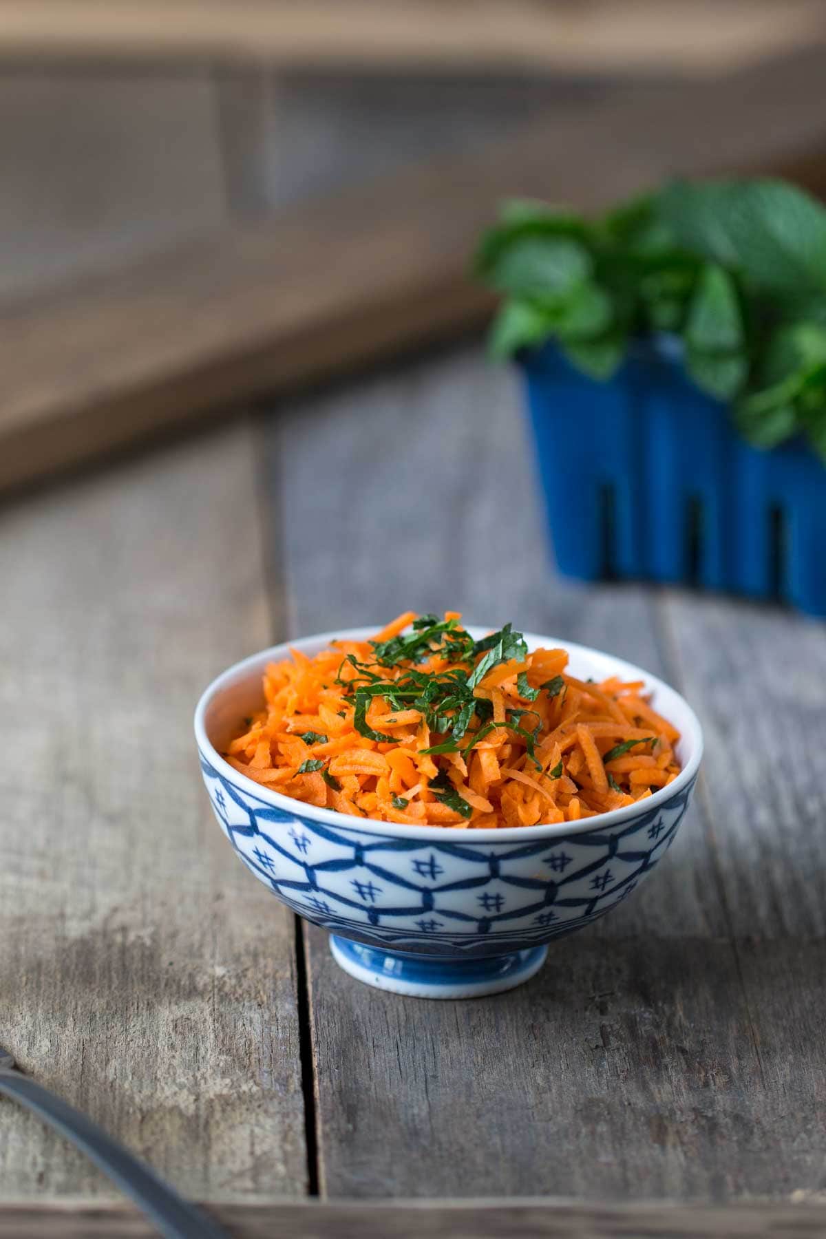 Carrot Salad topped with mint in a blue and white bowl. 