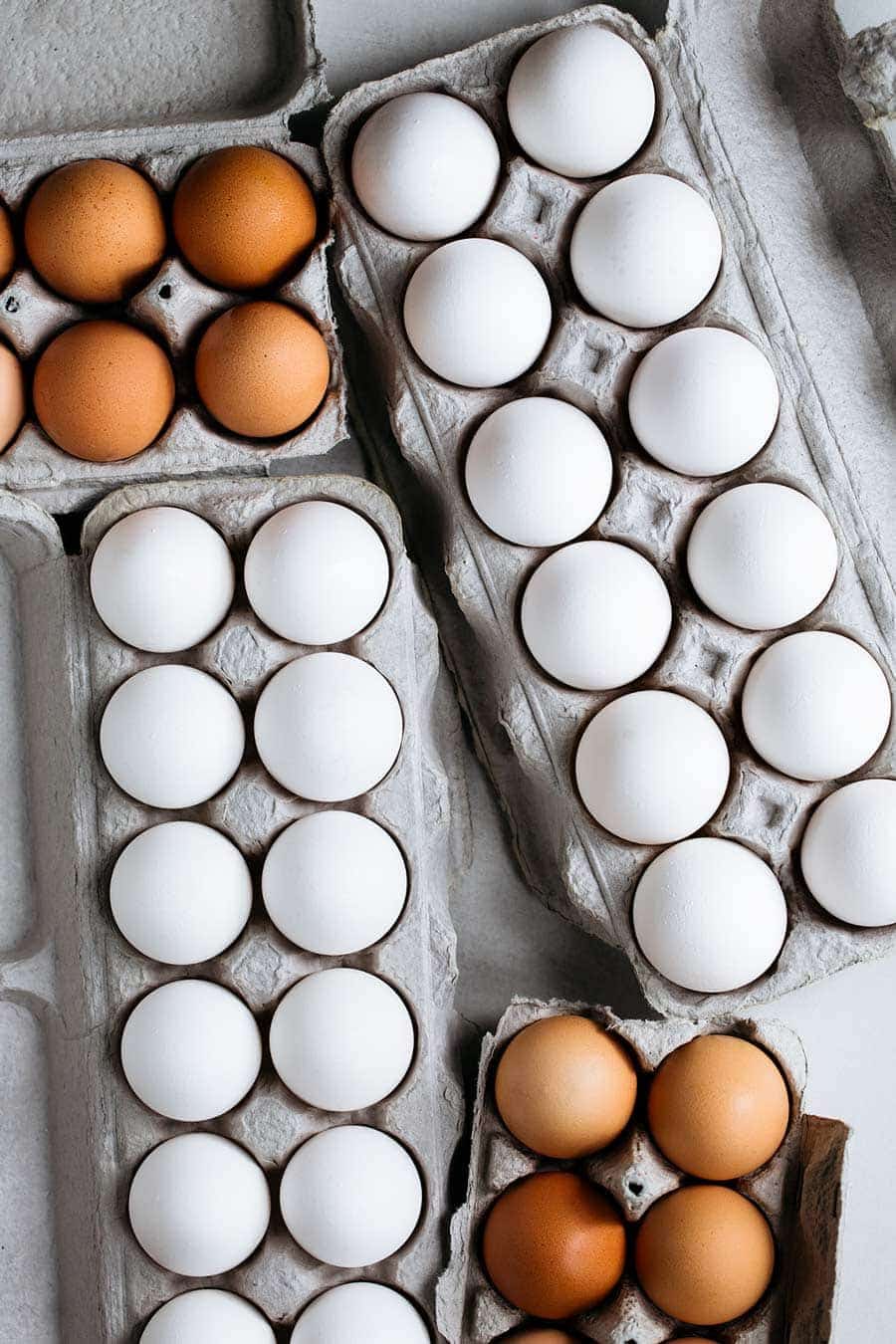 A variety of different sized and colored eggs in cartons