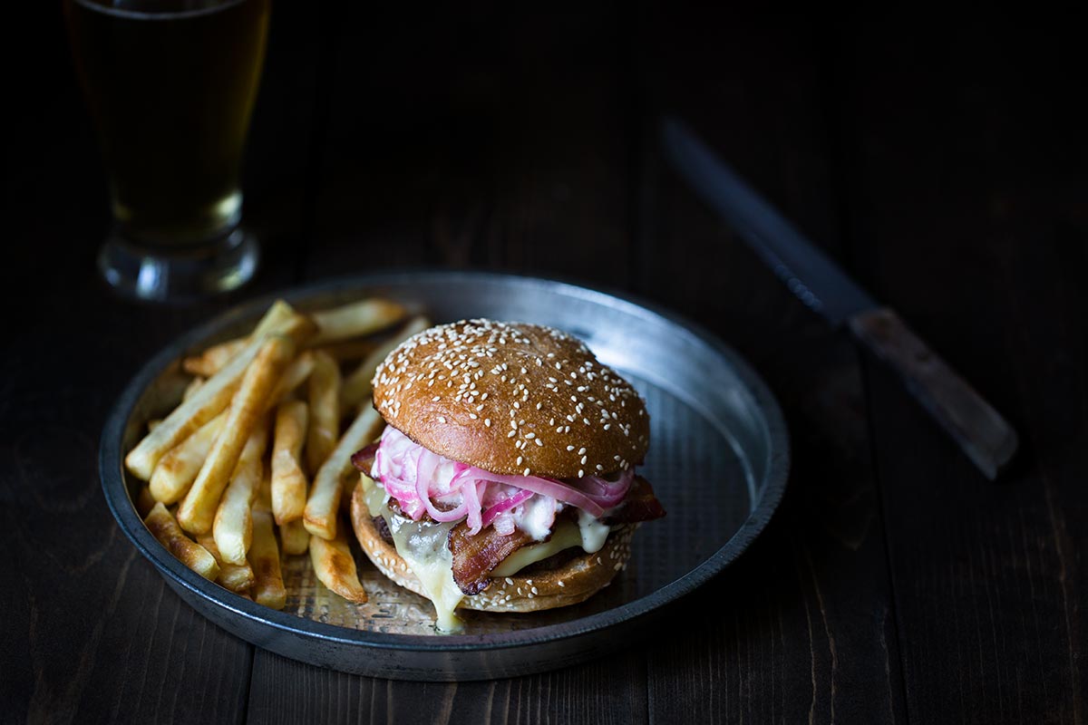 A raclette cheeseburger on a silver pie dish.
