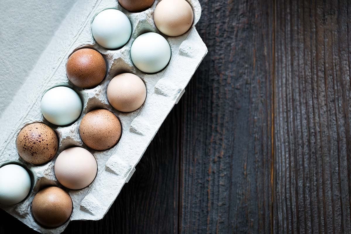 Multi-colored farm eggs in a carton.